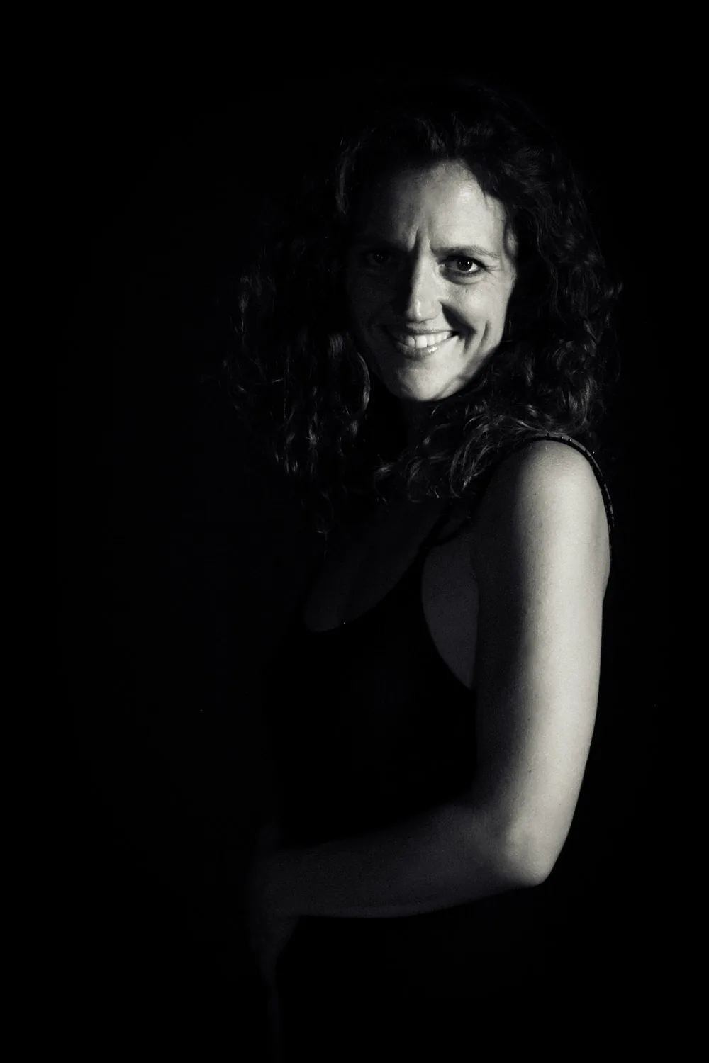 Portrait en noir et blanc de Barbara Lamothe, souriante, cheveux bouclés.